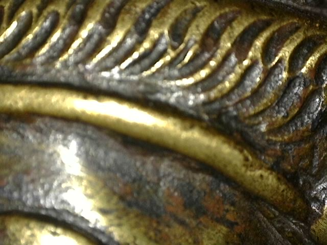 Microscoopdetail van vuurvergulding en slijtage op bronzen Brahma-beeld